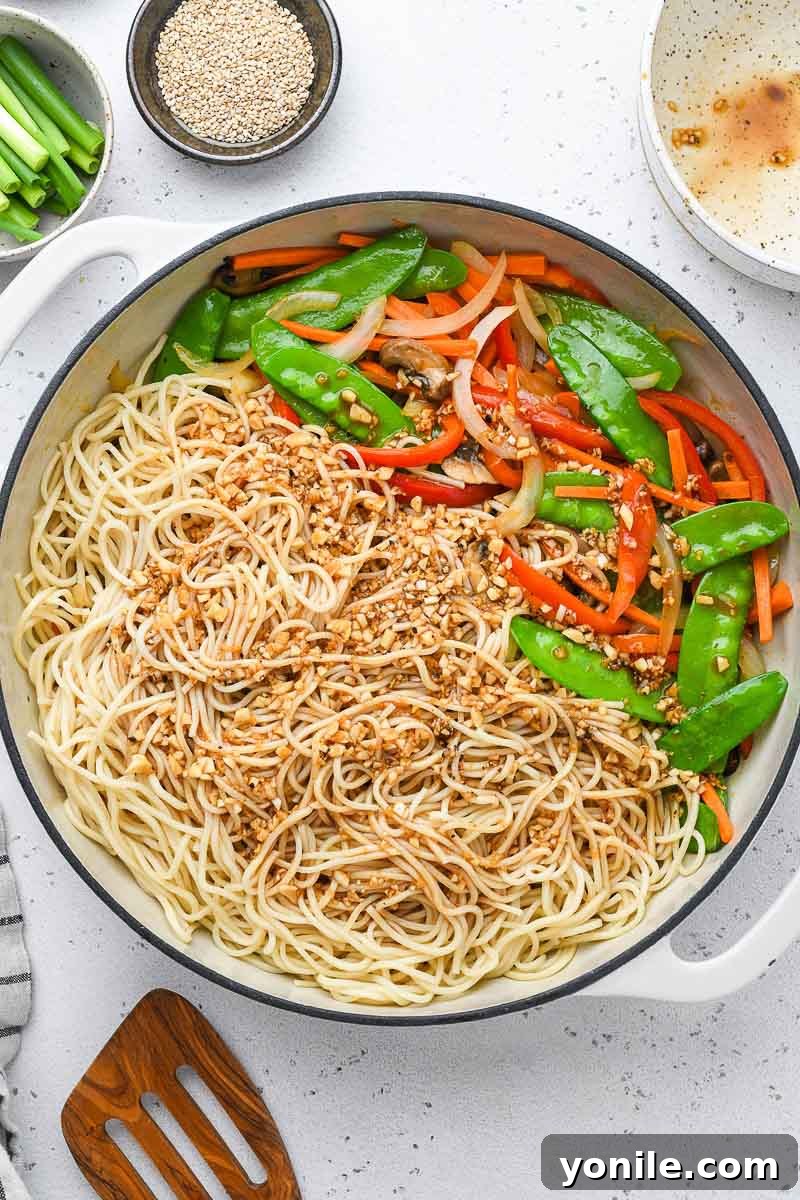 Speedy Weeknight Chicken Lo Mein 4 sauce poured over the lo mein noodles in a skillet