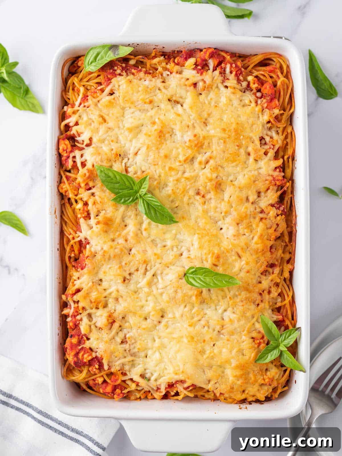 Simple Baked Spaghetti Casserole 7 Easy Spaghetti Pasta Bake, fresh out of the oven, topped with vibrant basil leaves and ready to be served.