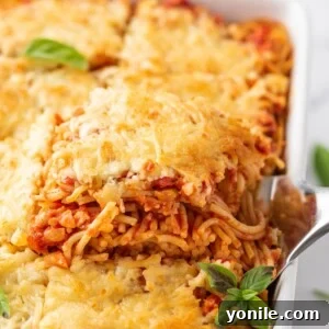 Simple Baked Spaghetti Casserole 10 Spatula lifting out a portion of the baked spaghetti, showcasing the melted cheese and rich sauce.