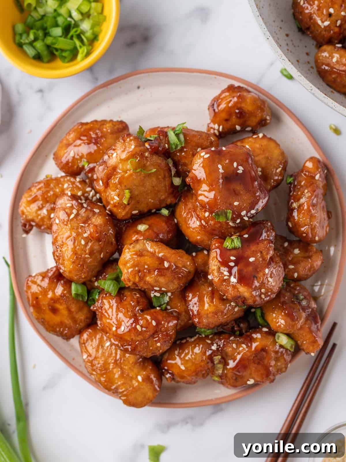 A beautifully plated dish of Crispy Honey Chicken, garnished with sesame seeds and green onions, ready to serve.