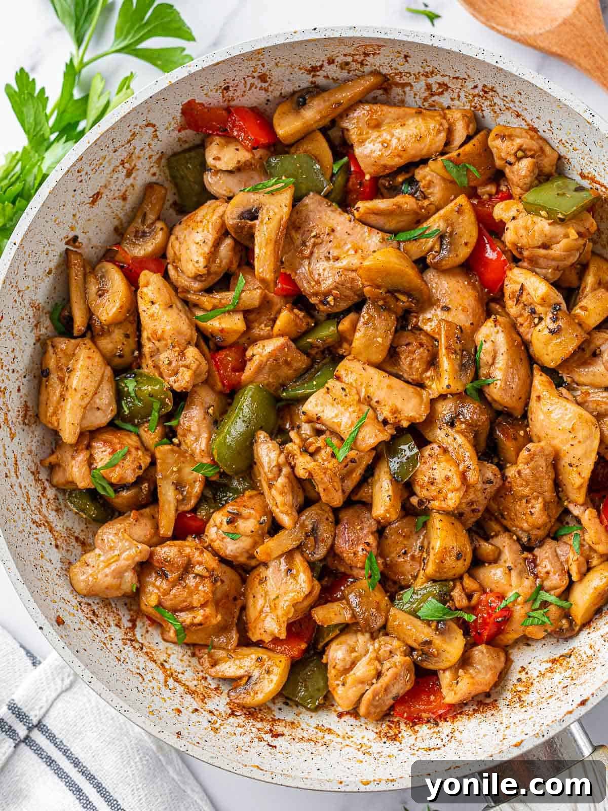 Sizzling Garlic Butter Mushroom Chicken Bites 2 Sizzling garlic butter chicken bites with mushrooms in a white skillet.