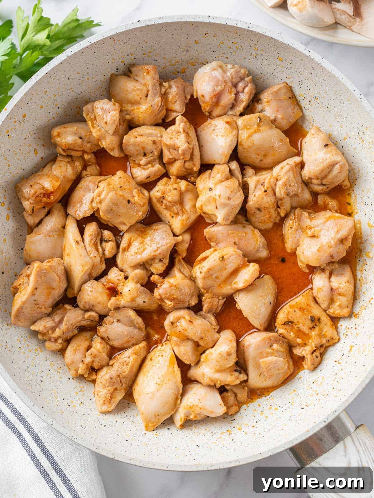 Sizzling Garlic Butter Mushroom Chicken Bites 4 Cubed chicken pieces searing in a pan, developing a golden-brown crust.