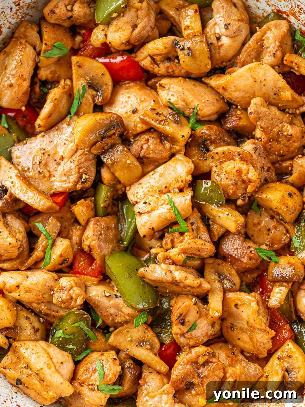 Sizzling Garlic Butter Mushroom Chicken Bites 8 Close-up of tender chicken bites glistening with garlic butter, mixed with colorful bell peppers and mushrooms.