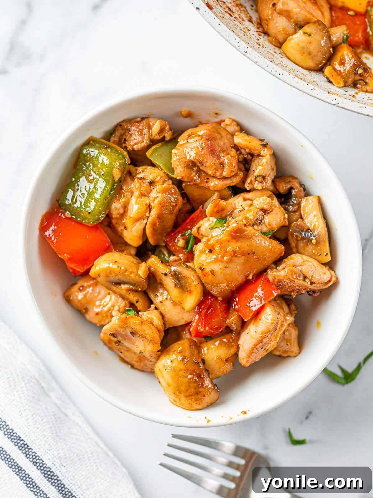 Sizzling Garlic Butter Mushroom Chicken Bites 9 A serving bowl filled with Garlic Mushroom Chicken Bites, garnished with fresh herbs, ready to be enjoyed.