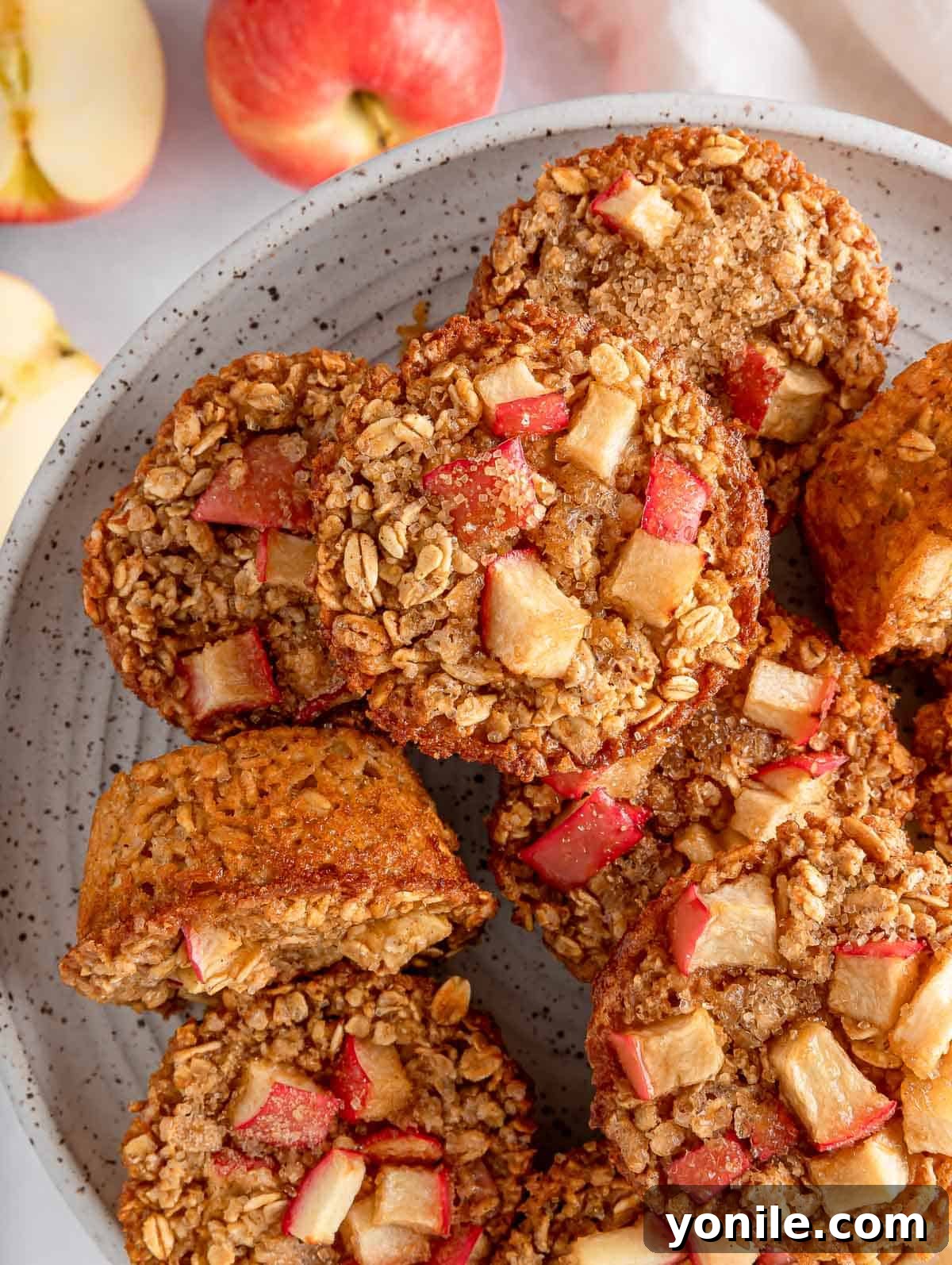 Overhead view of cinnamon baked apple oats cups on a plate, showcasing their golden-brown tops and apple chunks.