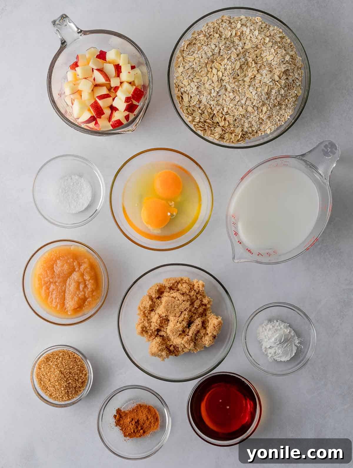 Ingredients needed to make cinnamon baked apple oats cups, including oats, apples, milk, and spices.