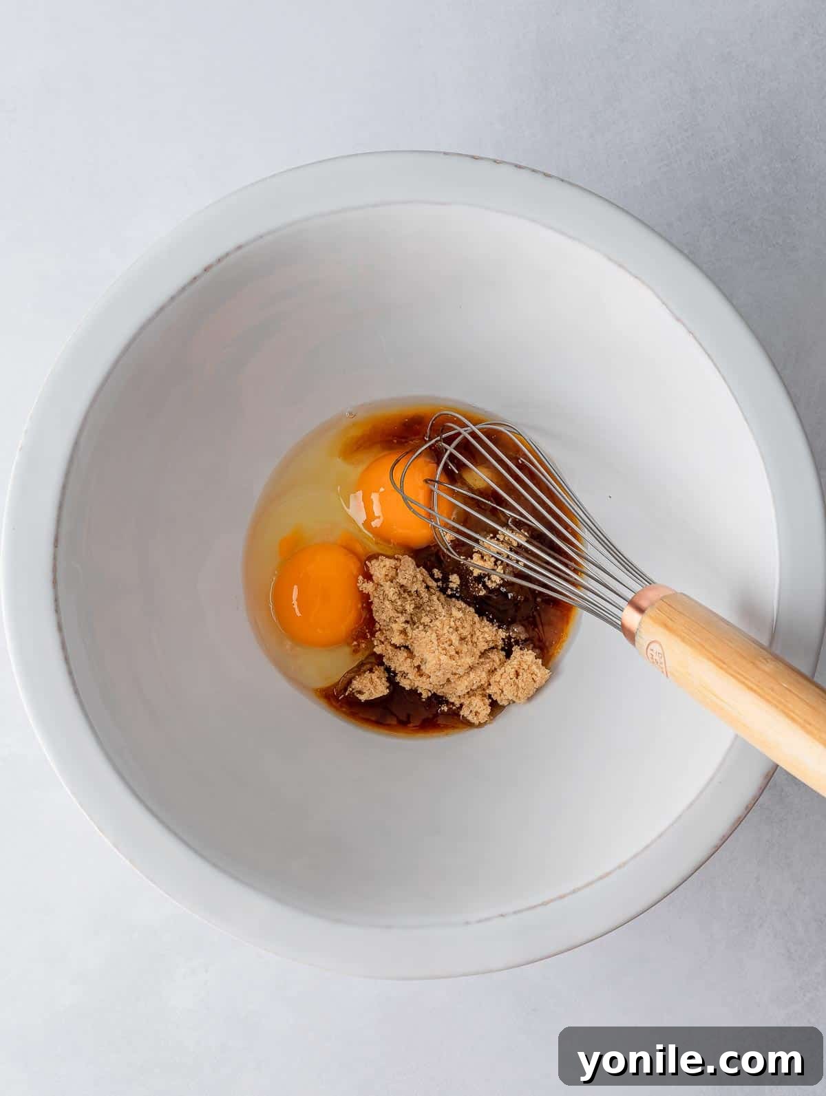 Wet ingredients added to a bowl with a whisk, showing the start of the mixing process.