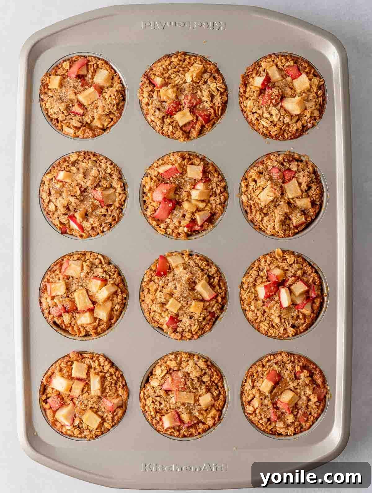 A muffin tin with freshly baked cinnamon apple oats cups, golden and inviting.