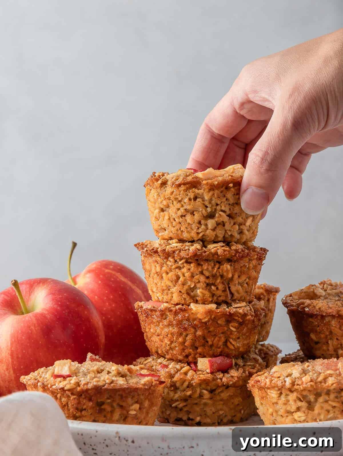 Cinnamon baked apple oats cups stacked on top of each other on a plate, highlighting their appetizing appearance.