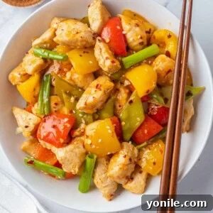 A plate of Szechuan chicken with chopsticks on the side.