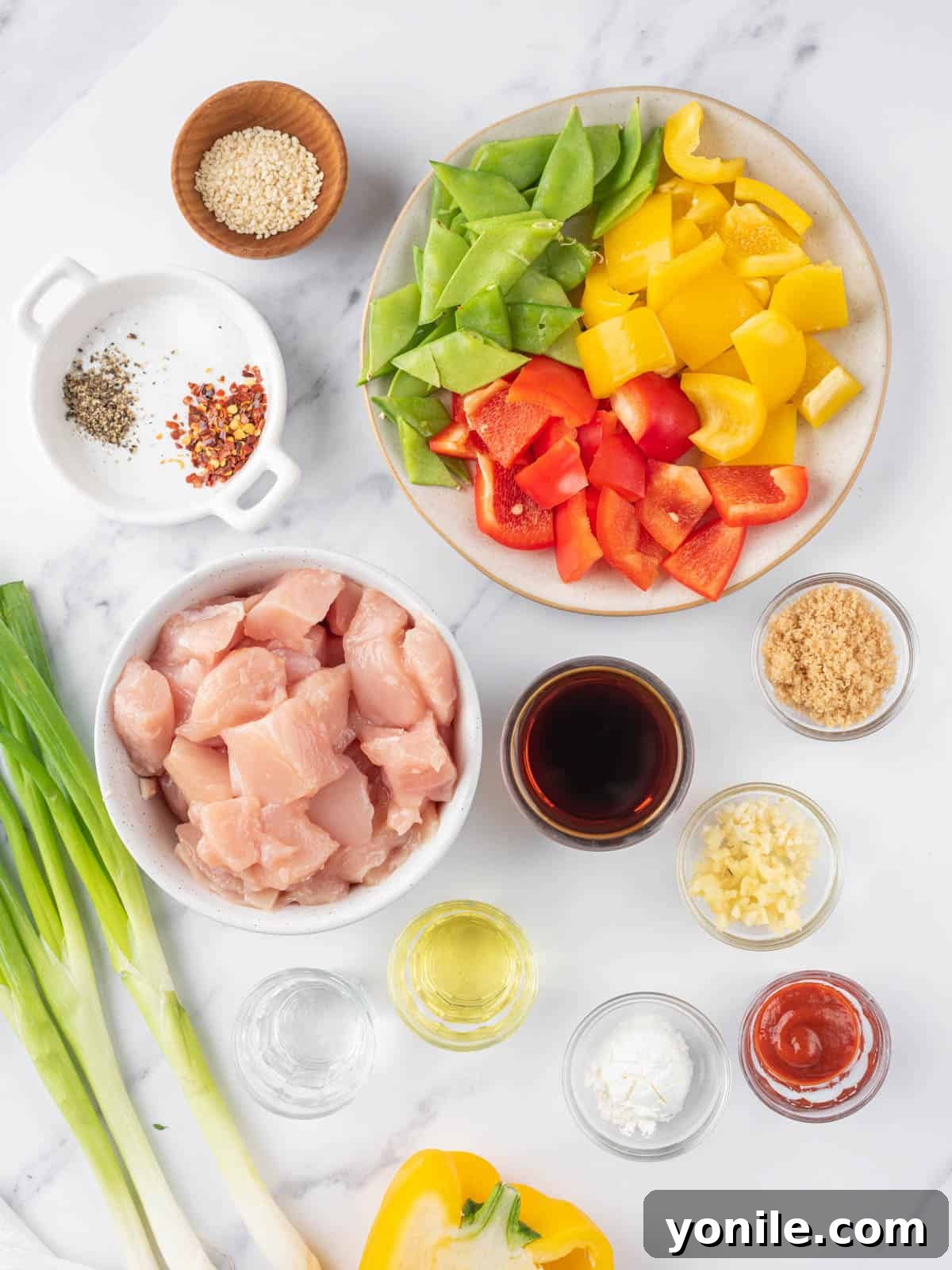 A selection of fresh ingredients for Szechuan chicken laid out on a cutting board.