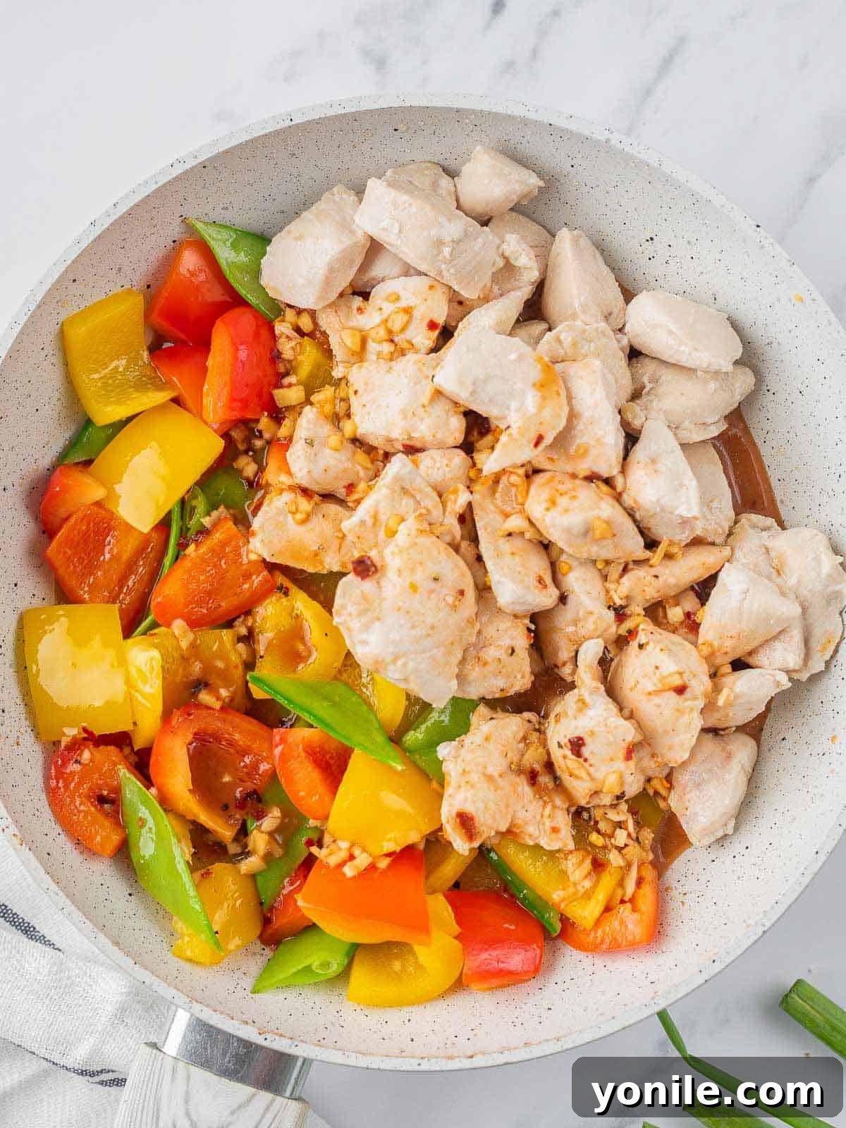 Previously cooked chicken being added back into the pan with the stir-fried vegetables.