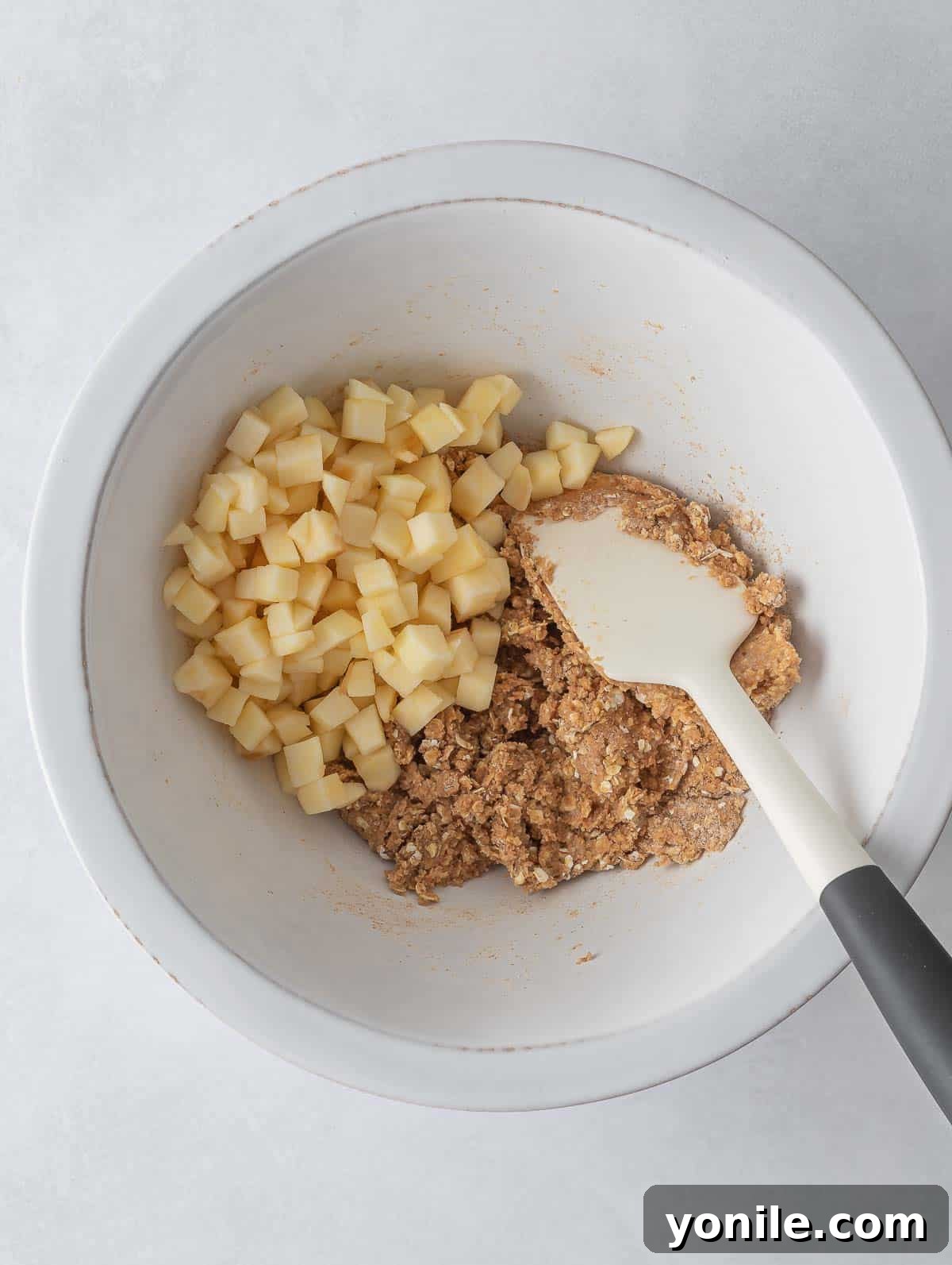 Finely diced apples being folded into the cookie dough.