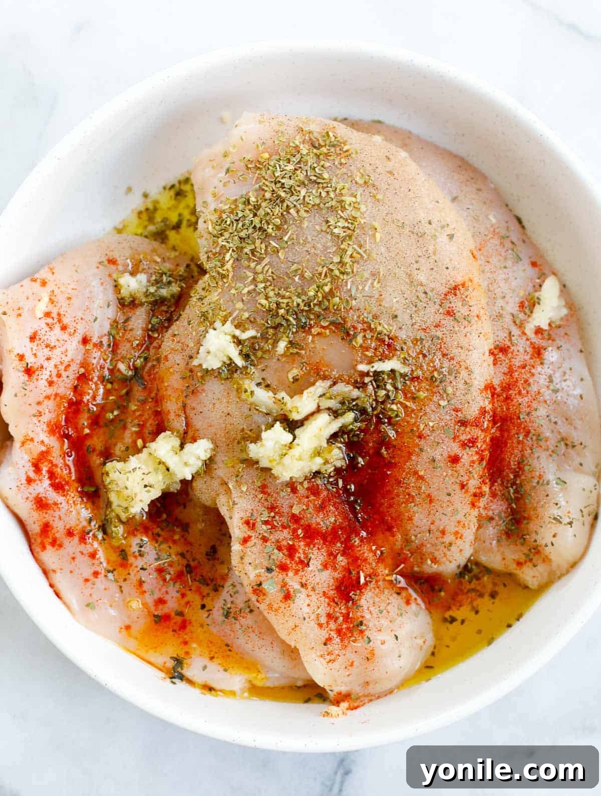 Chicken breast seasoned in a bowl, ready for searing.