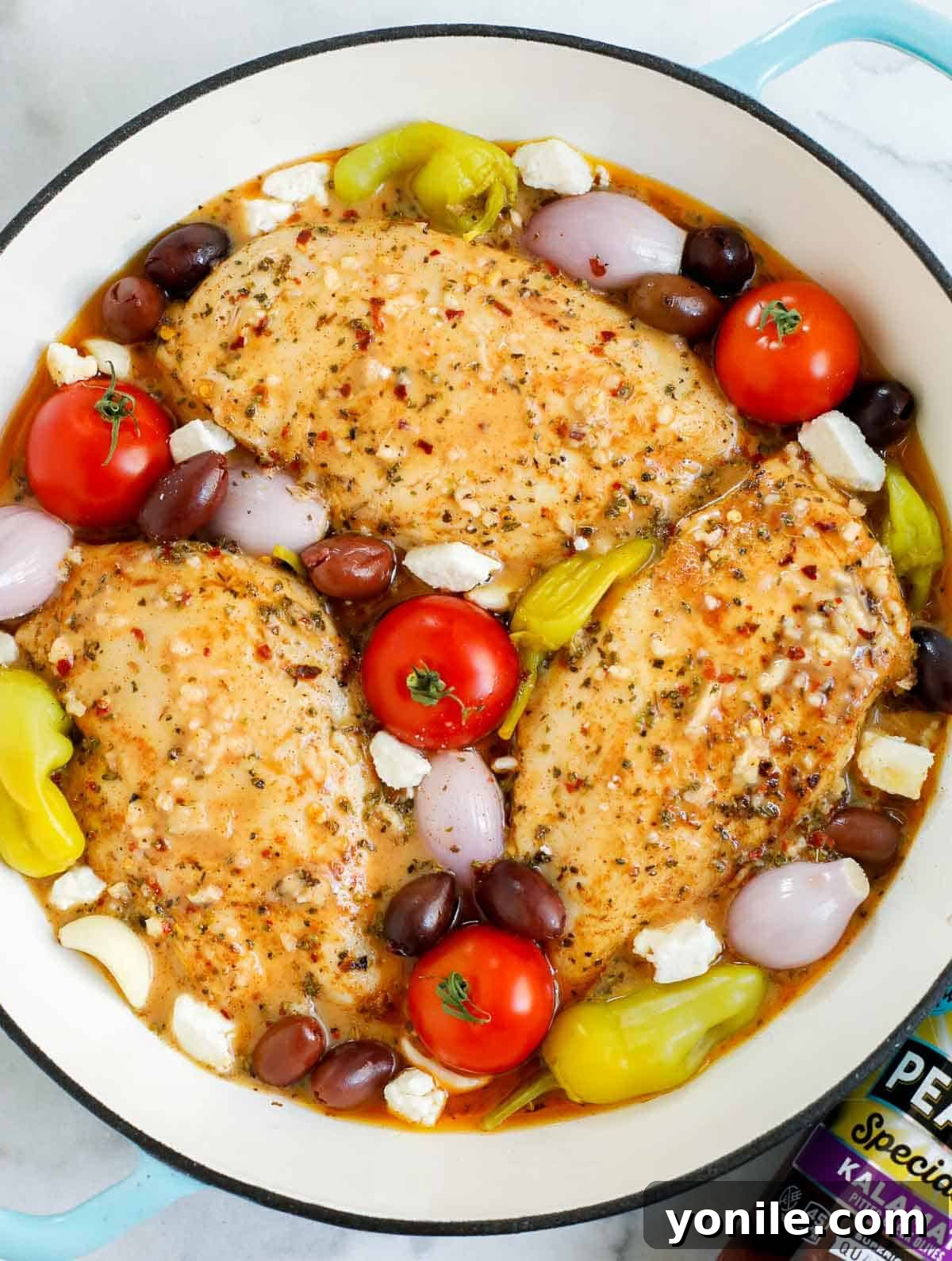 A pan of baked Greek chicken with all ingredients assembled and ready for the oven.