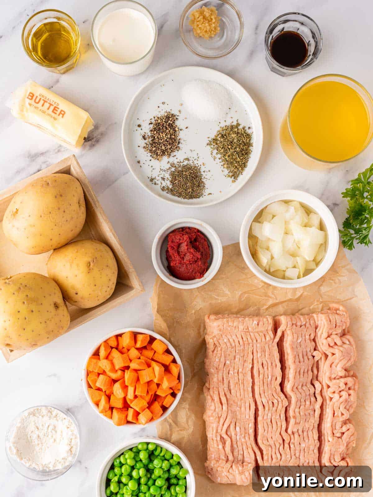 A curated display of fresh ingredients for Chicken Shepherd's Pie, including ground chicken, vegetables, and herbs