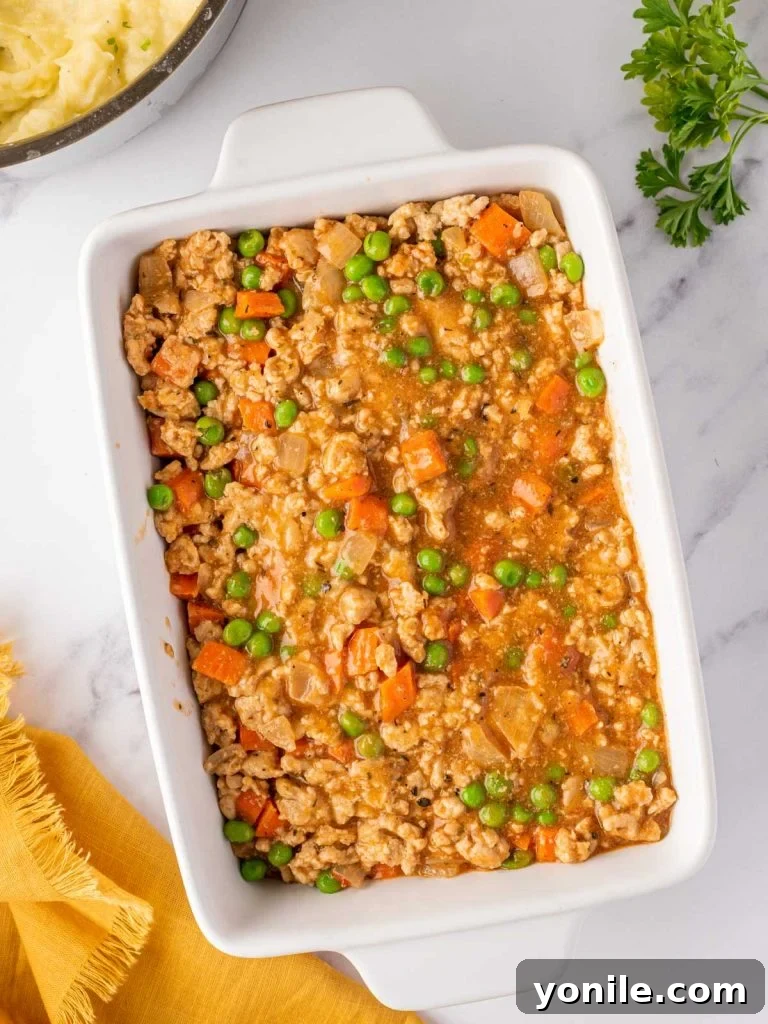 Shepherds pie filling spread evenly in a rectangular baking dish
