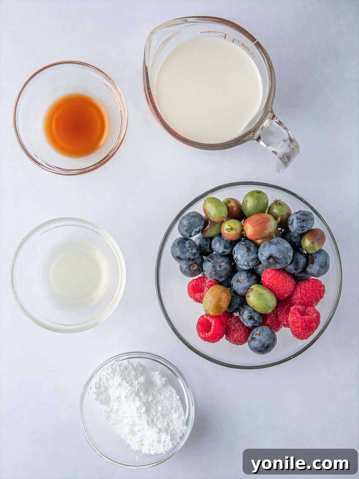 Fresh berries and heavy whipping cream, key ingredients for Pavlova topping, arranged on a surface.