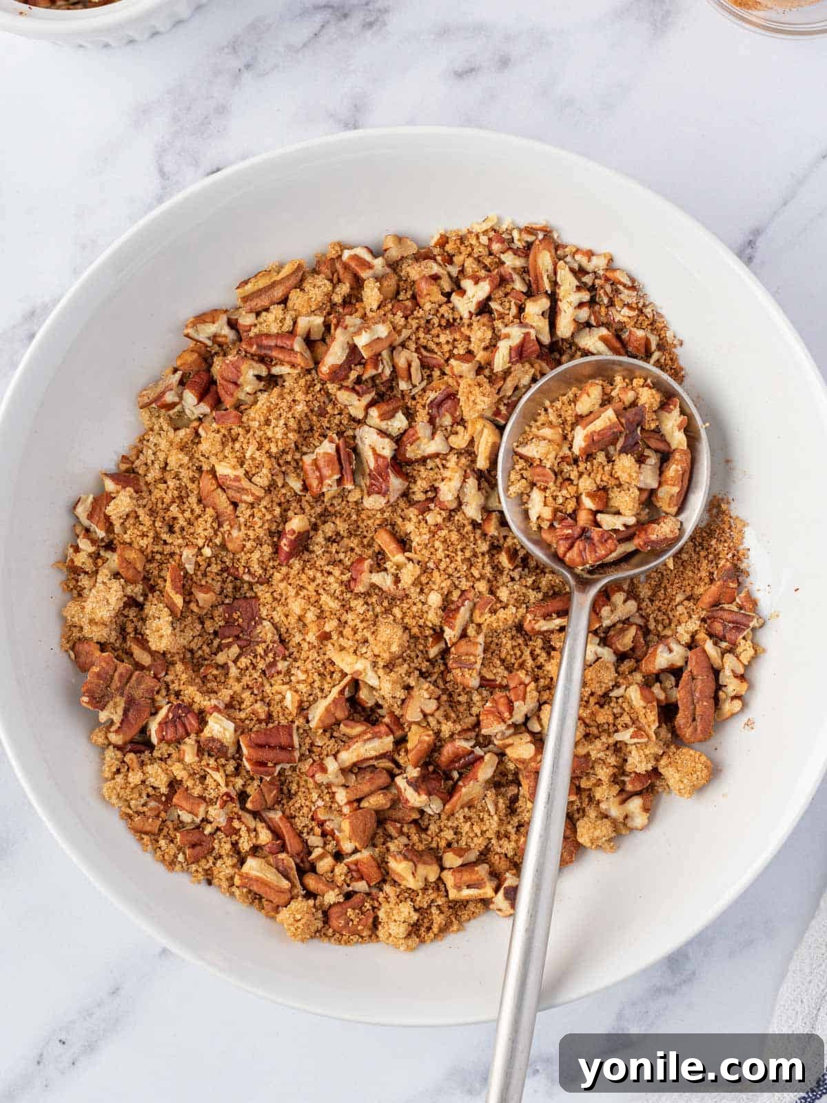 Close-up of the pecan, brown sugar, and cinnamon topping mixture in a bowl, ready to be sprinkled
