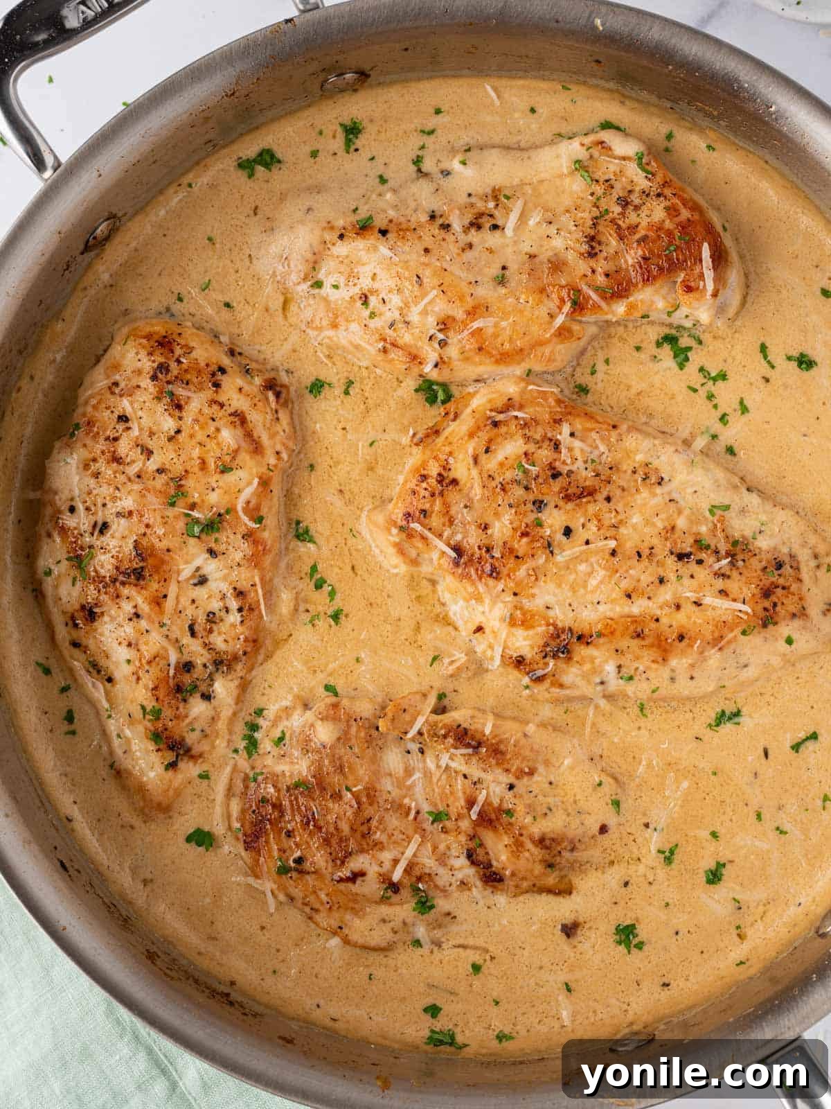 A large skillet filled with perfectly cooked creamy garlic parmesan chicken breasts, glistening with rich sauce, ready to be served as a hearty family meal.