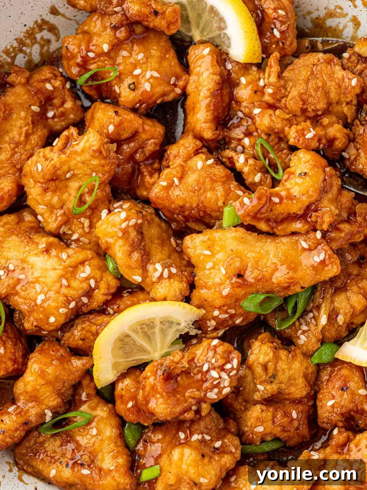 Zesty Lemon Chicken 11 Close up shot of Chinese lemon chicken topped with sesame seeds and a lemon wedge.