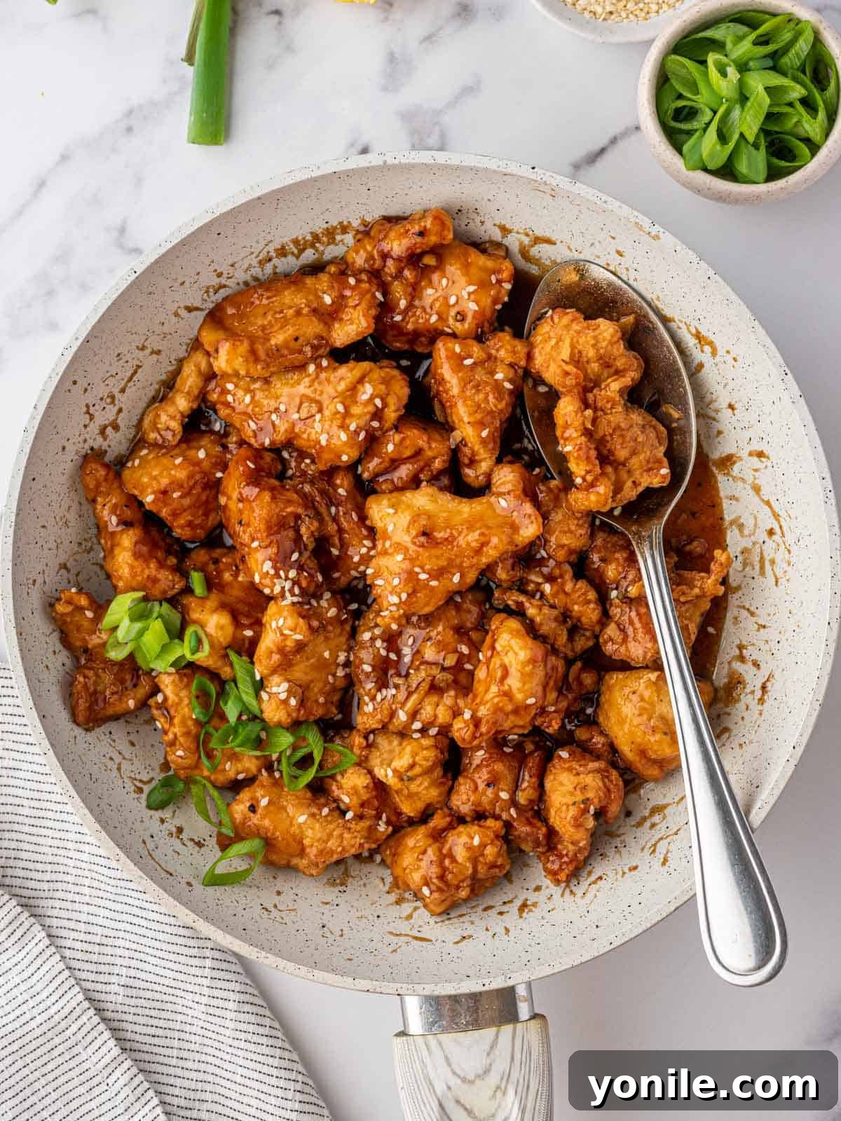 Zesty Lemon Chicken 9 A large bowl of Asian lemon chicken with a serving spoon.