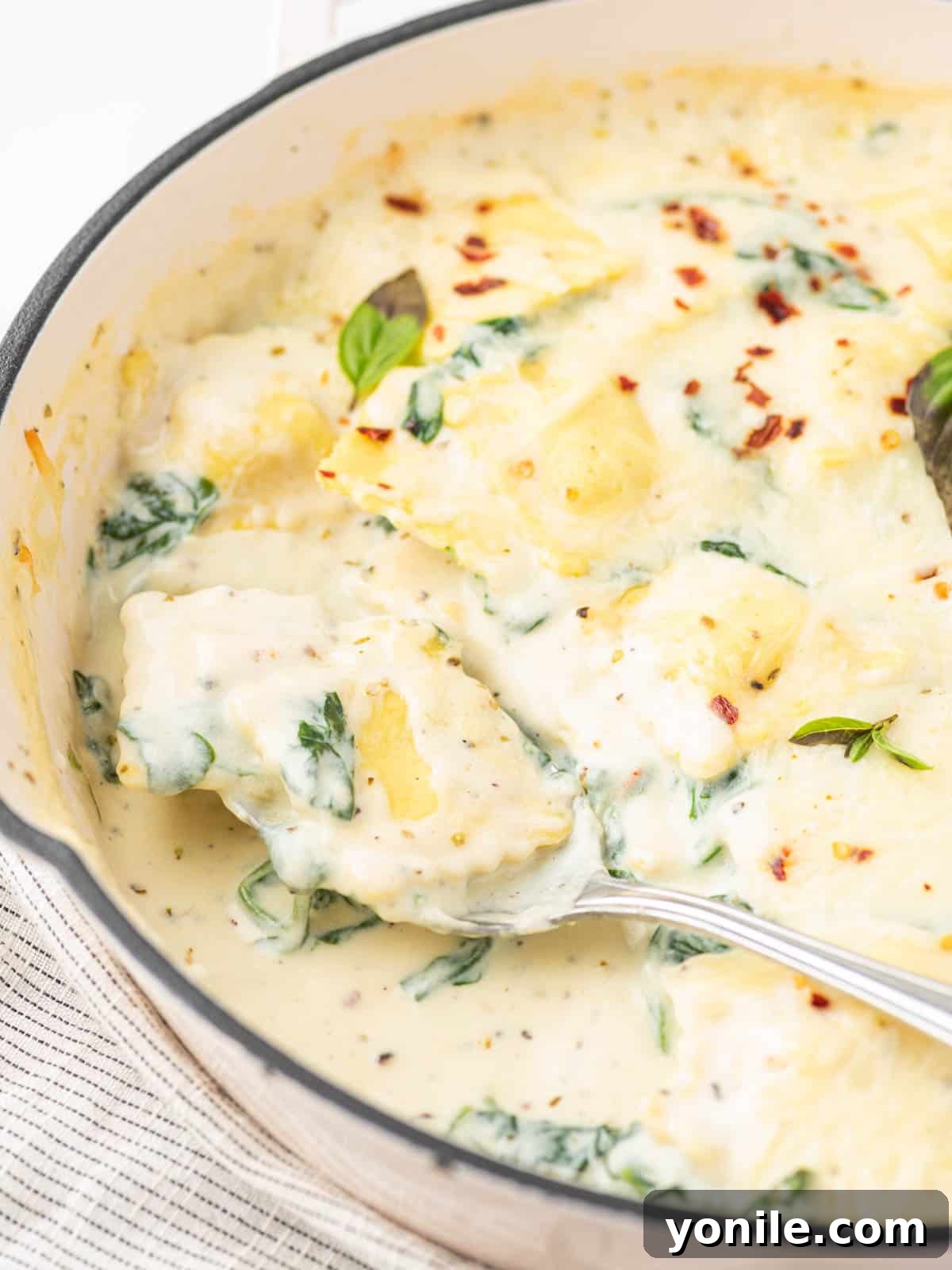 Luscious Spinach and Cheese Ravioli 9 A spoon scooping a portion of baked ravioli with spinach and cheese.