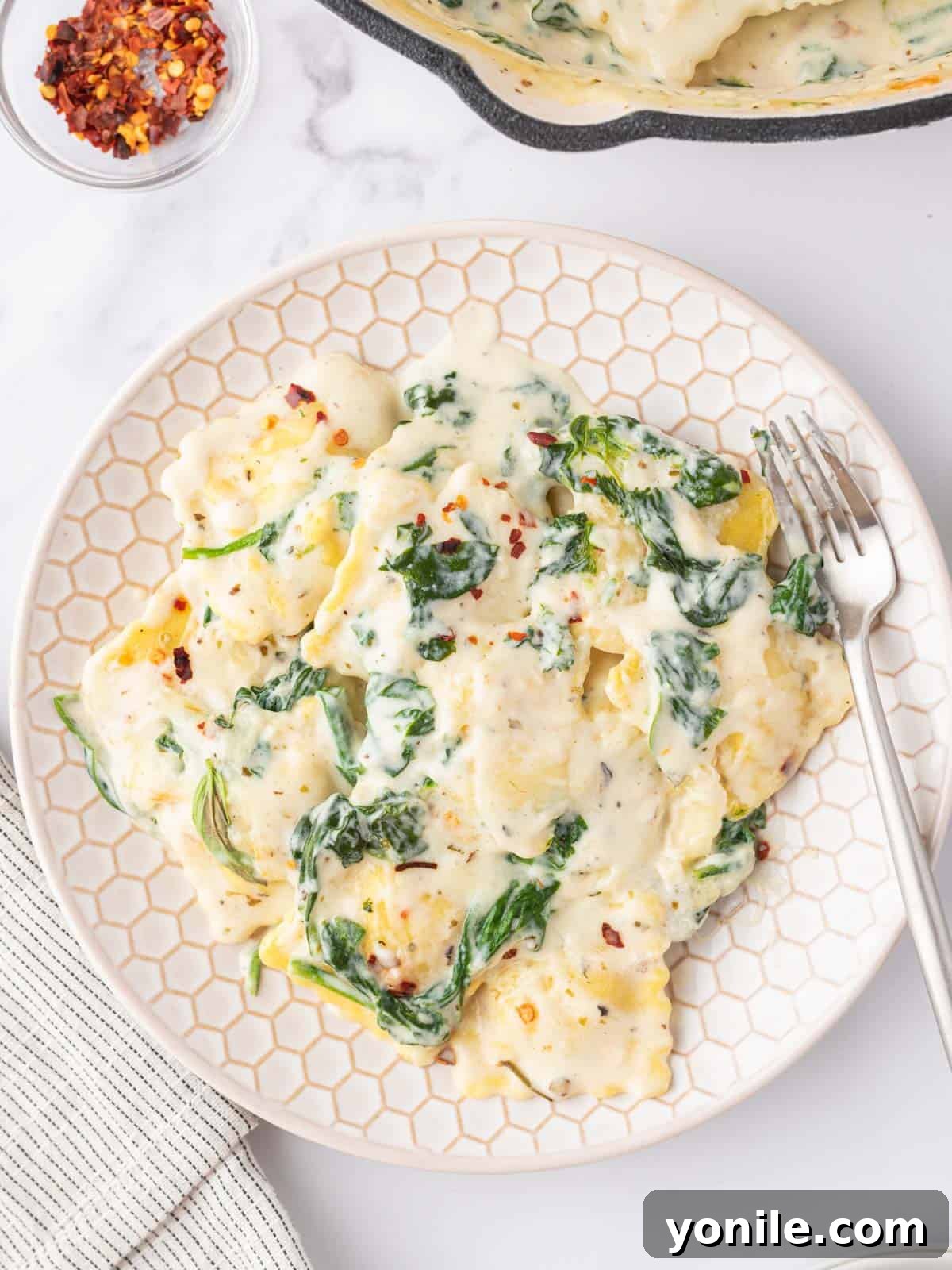 Luscious Spinach and Cheese Ravioli 10 A serving of spinach and cheese ravioli on a white plate with a fork.