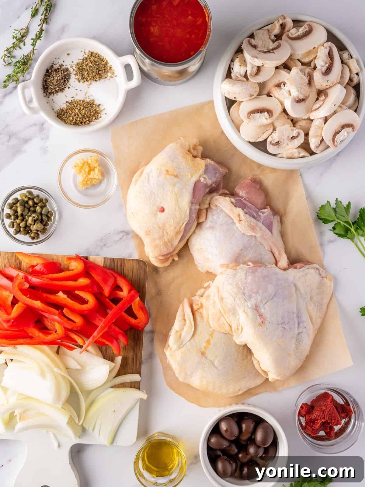 Classic Italian Hunter's Chicken 3 A vibrant selection of fresh ingredients laid out for making the best easy chicken cacciatore, including chicken thighs, vegetables, and seasonings.