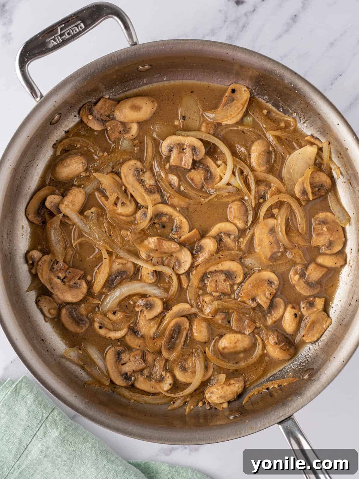 The remaining half of the mushroom mixture simmering in a skillet with chicken broth.
