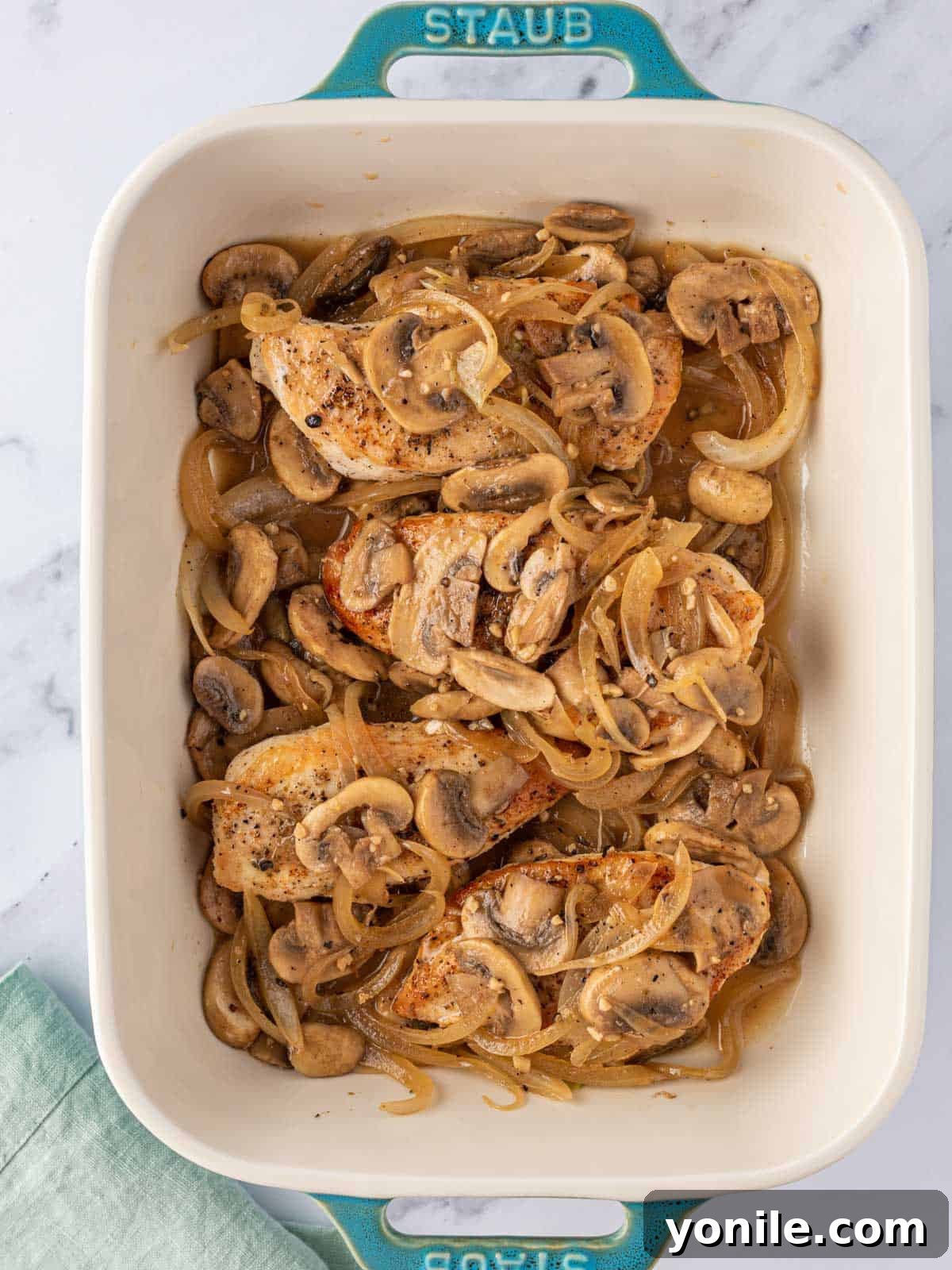 The remaining mushroom mixture and broth poured over the chicken breasts in the baking dish.