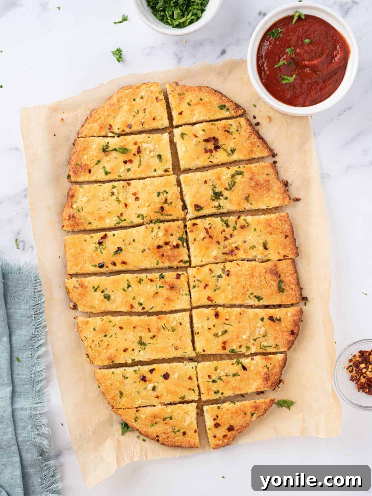 Overhead view of low carb garlic bread cut into rectangular slices with marinara on the side.
