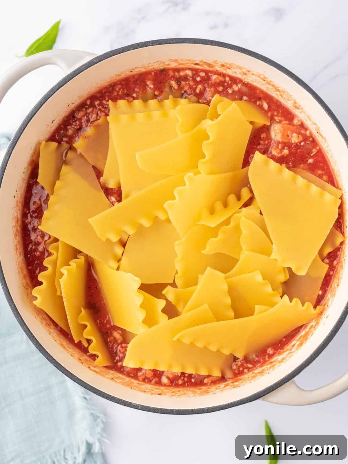 Adding broken lasagna noodles for lasagna soup into the boiling broth.