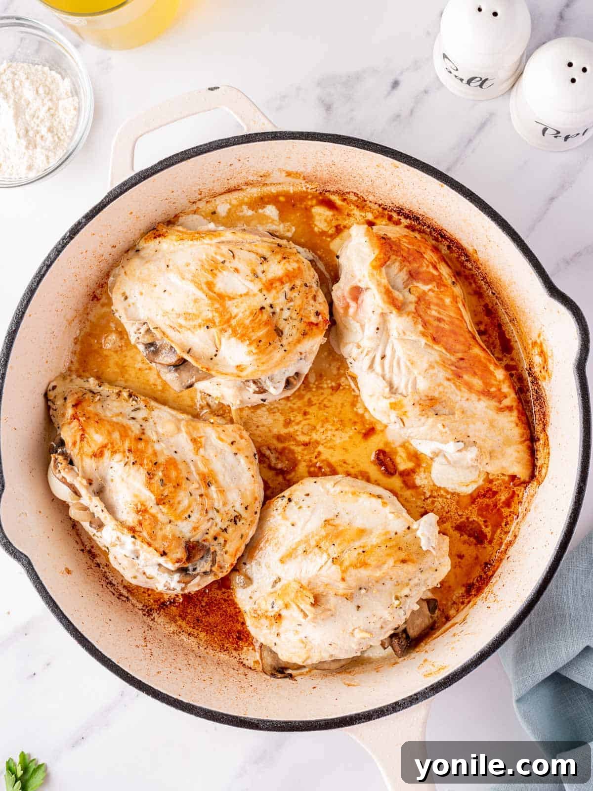 Chicken in a skillet after being seared and browned.