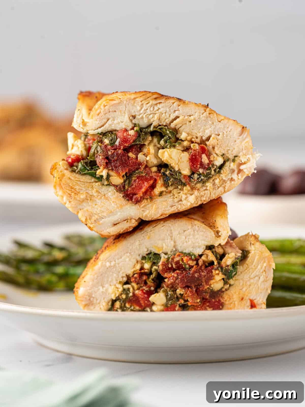 Two halves of a Mediterranean stuffed chicken breast stacked on top of each other, showcasing the rich, colorful filling.