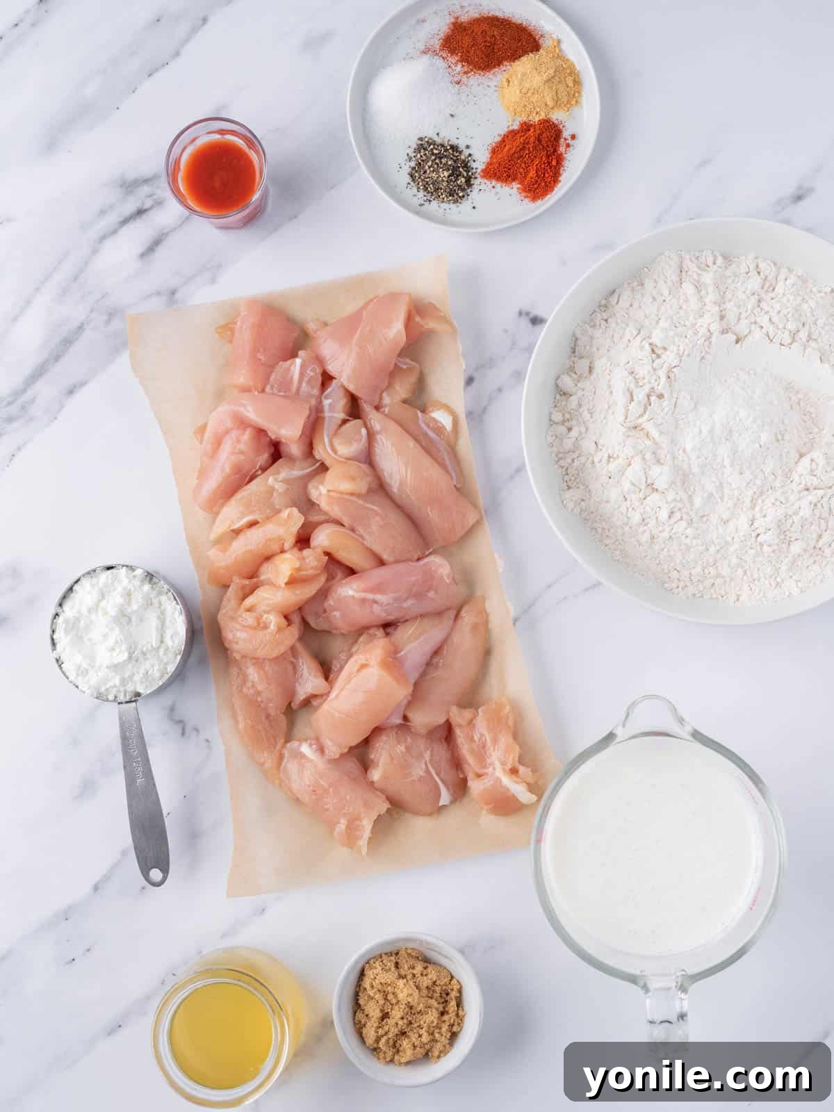 KFC's Fiery Nashville Tenders 3 Ingredients needed to make Nashville hot chicken tenders laid out on a wooden surface.