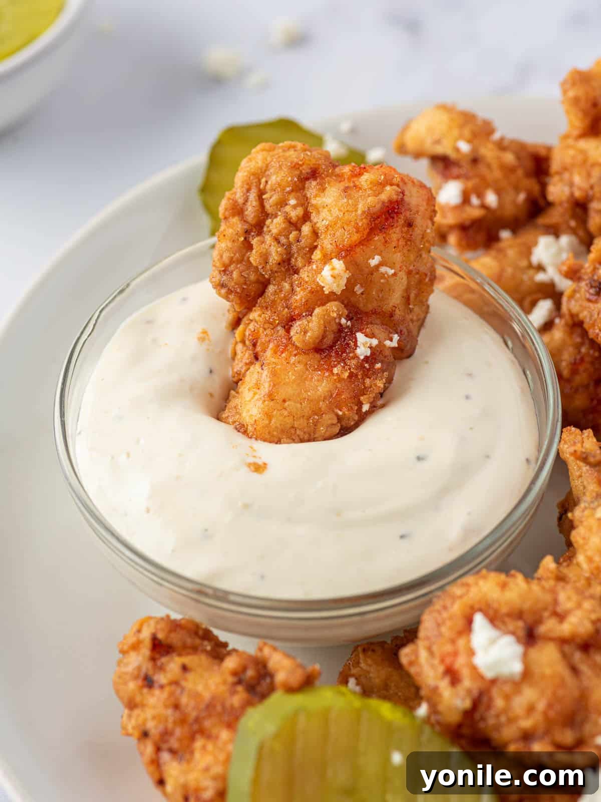 KFC's Fiery Nashville Tenders 10 A Nashville hot chicken tender being dipped into a creamy sauce.