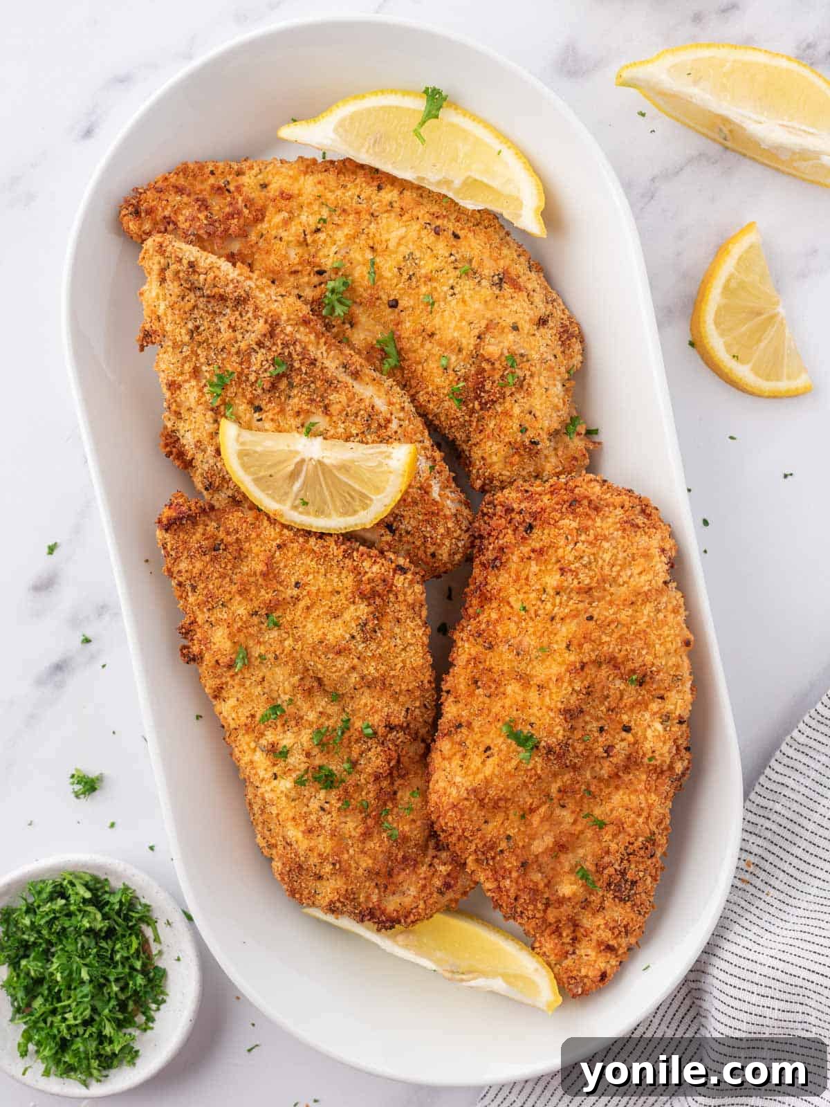 Crispy Air Fryer Chicken Cutlets 2 Golden-brown, crispy air fryer chicken cutlets served on a platter, garnished with fresh parsley and lemon wedges.