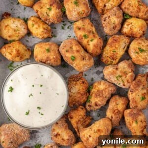 Popcorn chicken air fryer on a tray with a bowl of dip.
