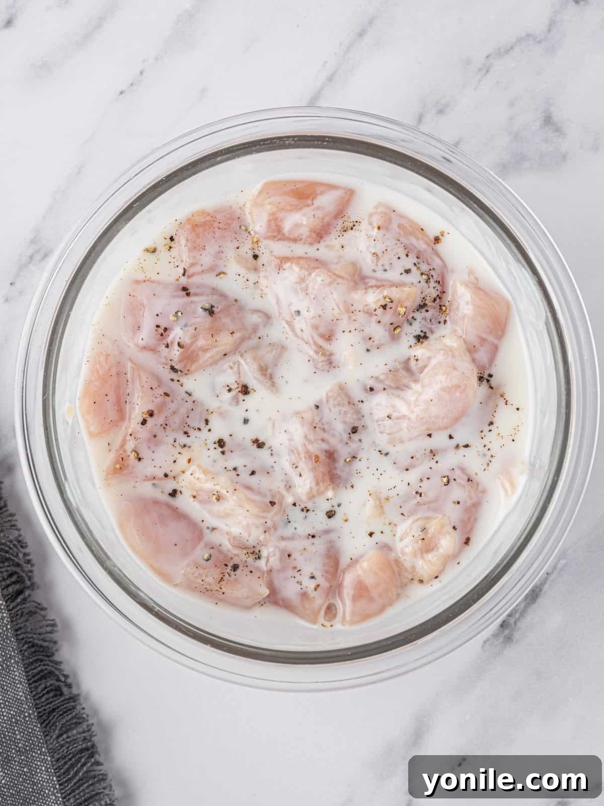 Golden Air Fryer Chicken Bites 4 Cubed chicken tenders marinating in buttermilk.
