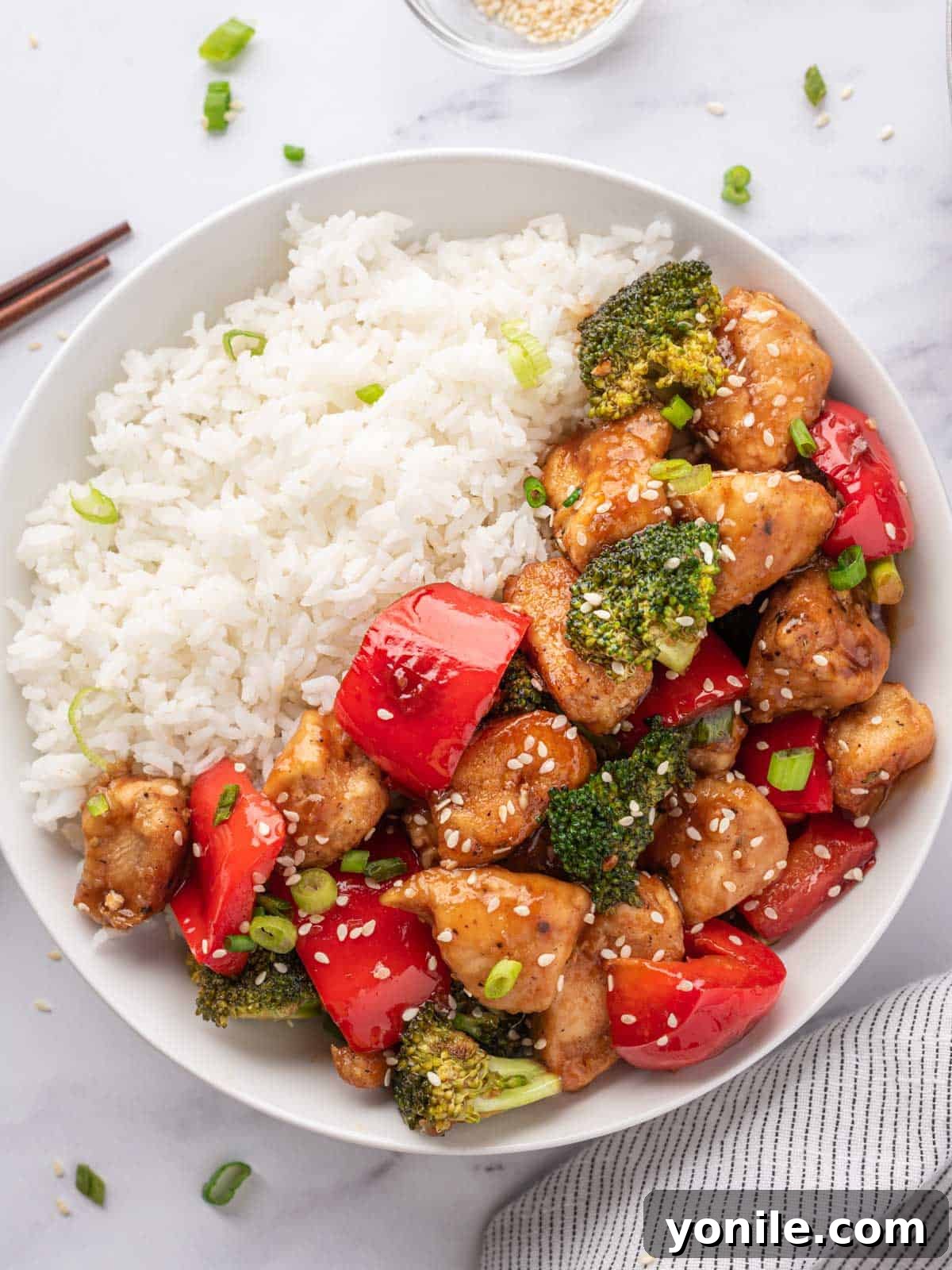 White bowl with rice and topped with Teriyaki chicken stir fry recipe.