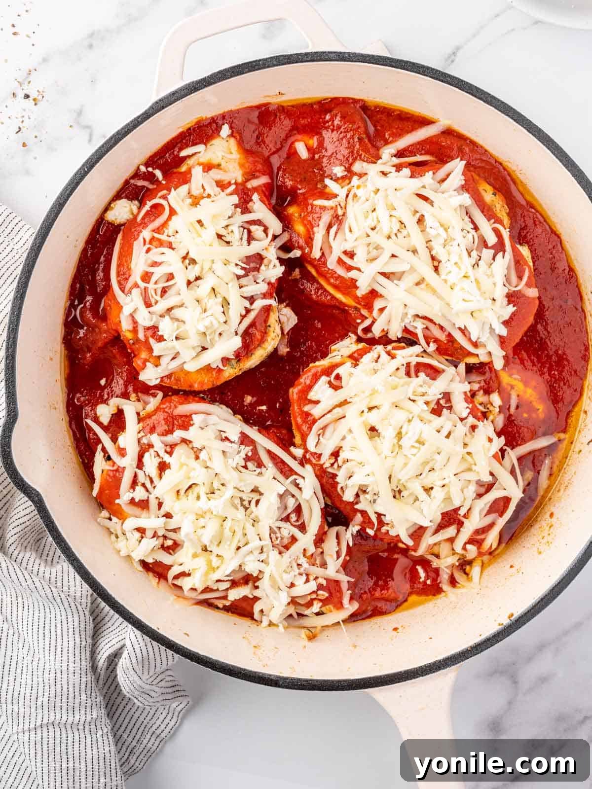 Chicken topped with sauce and cheese.