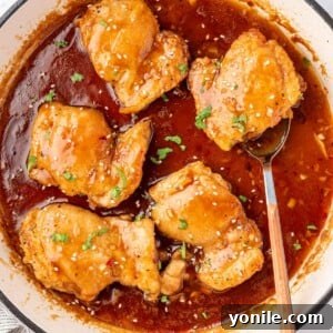 A pan of honey garlic chicken with a spoon under a chicken.