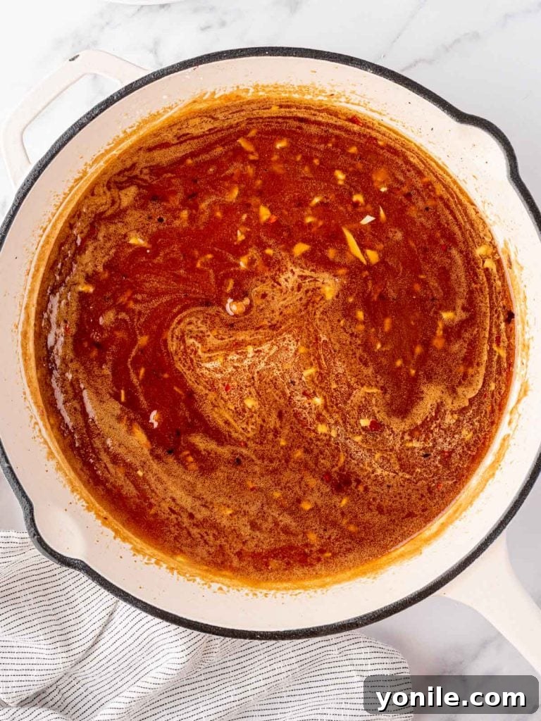 The honey garlic sauce simmering and thickening in the skillet, with a rich, glossy texture.