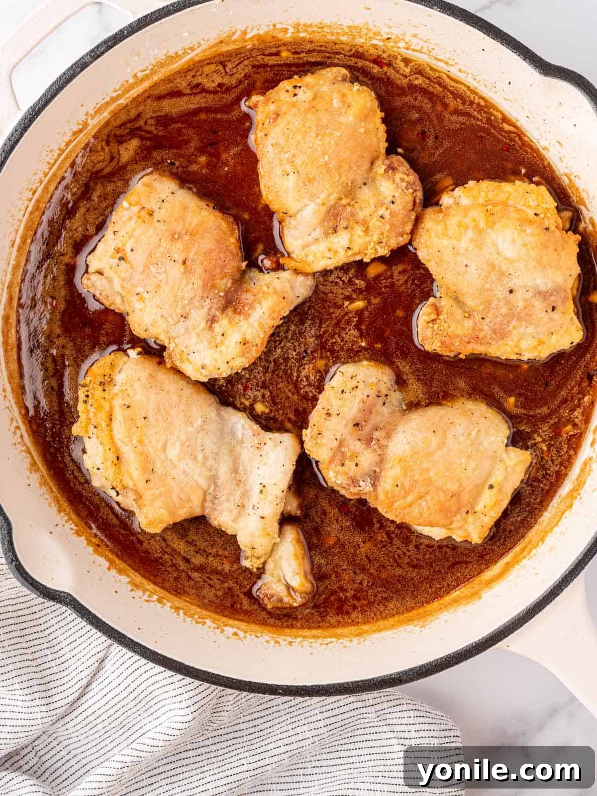 The seared chicken thighs returned to the skillet, now coated in the rich, sticky honey garlic sauce.