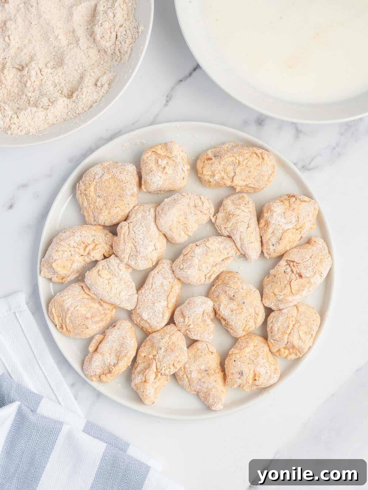 Plate of buttermilk and flour-coated chicken pieces, ready for frying.