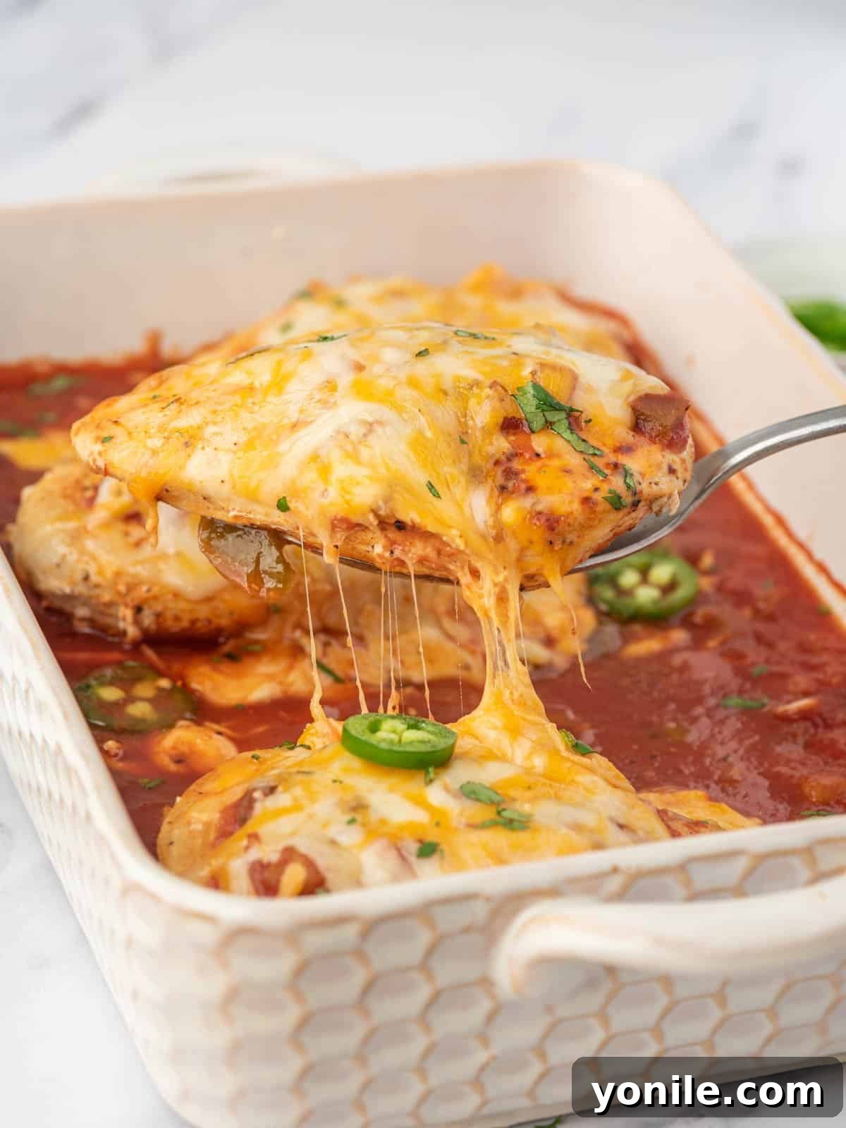A serving of baked salsa chicken lifted from the baking dish.