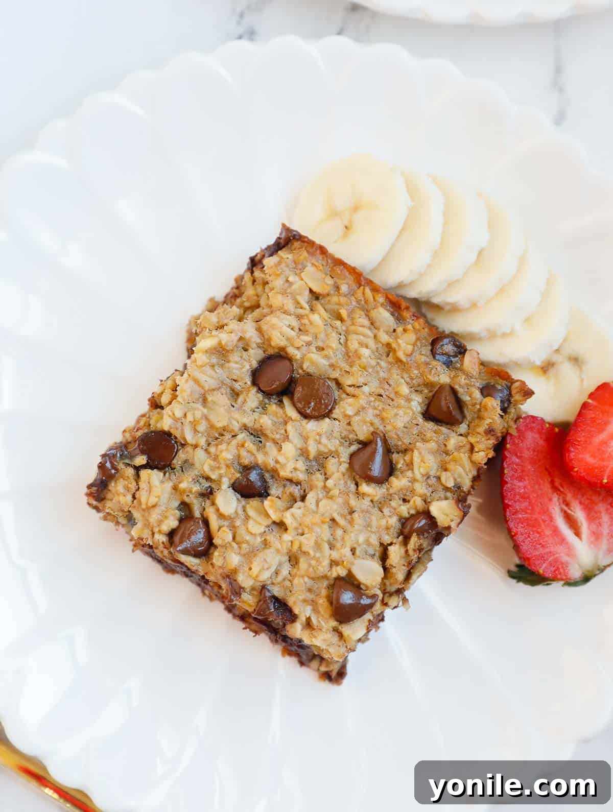 Chocolate Chip Oat Delight 2 A slice of chocolate chip baked oatmeal on a white plate, garnished with fresh berries and a hint of maple syrup, ready to be enjoyed as a healthy breakfast.