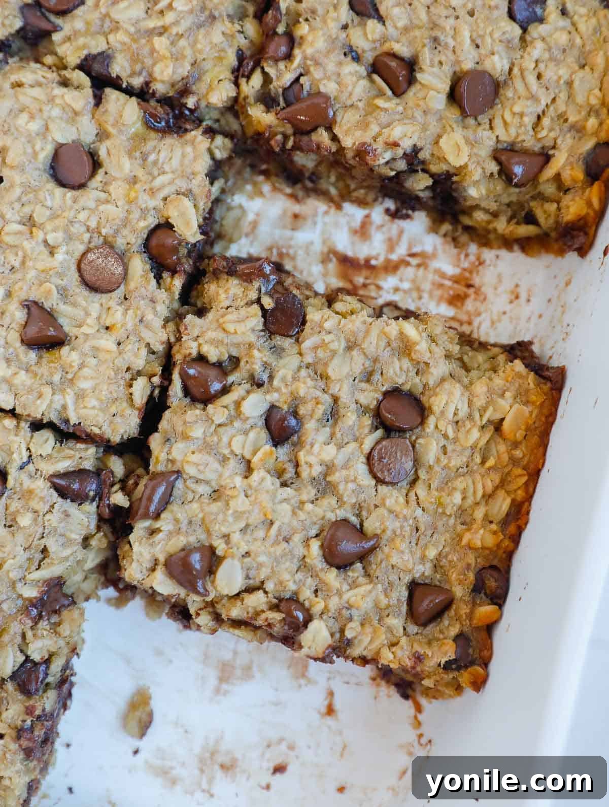 Chocolate Chip Oat Delight 7 Close-up shot of perfectly baked chocolate chip oatmeal cut into neat squares within a baking dish, showcasing its moist texture and melted chocolate chips.