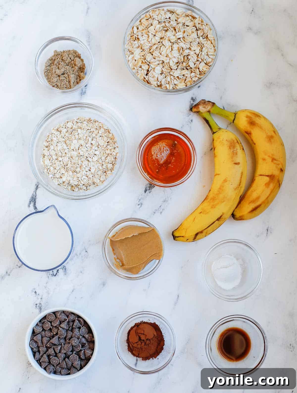 A curated display of all the essential ingredients laid out neatly for baked chocolate oatmeal preparation, including oats, milk, bananas, and chocolate chips.